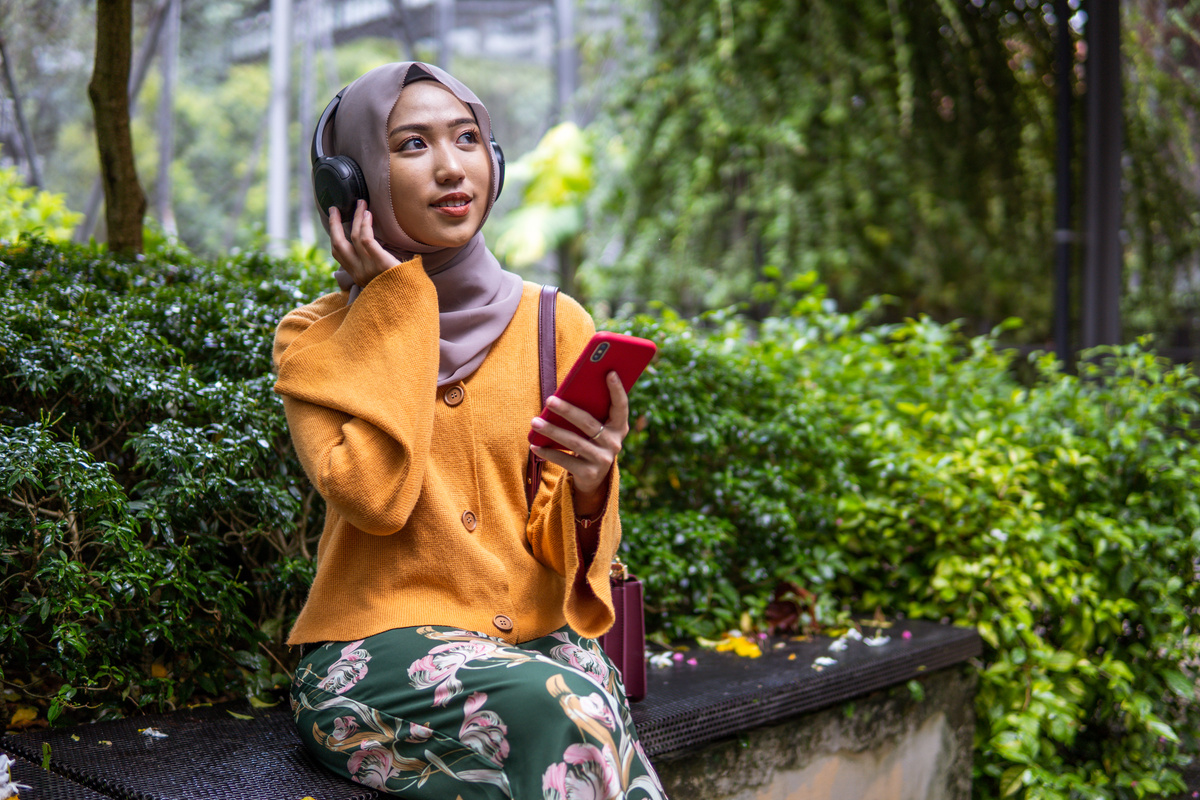 Beautiful asian women listen to podcast at park